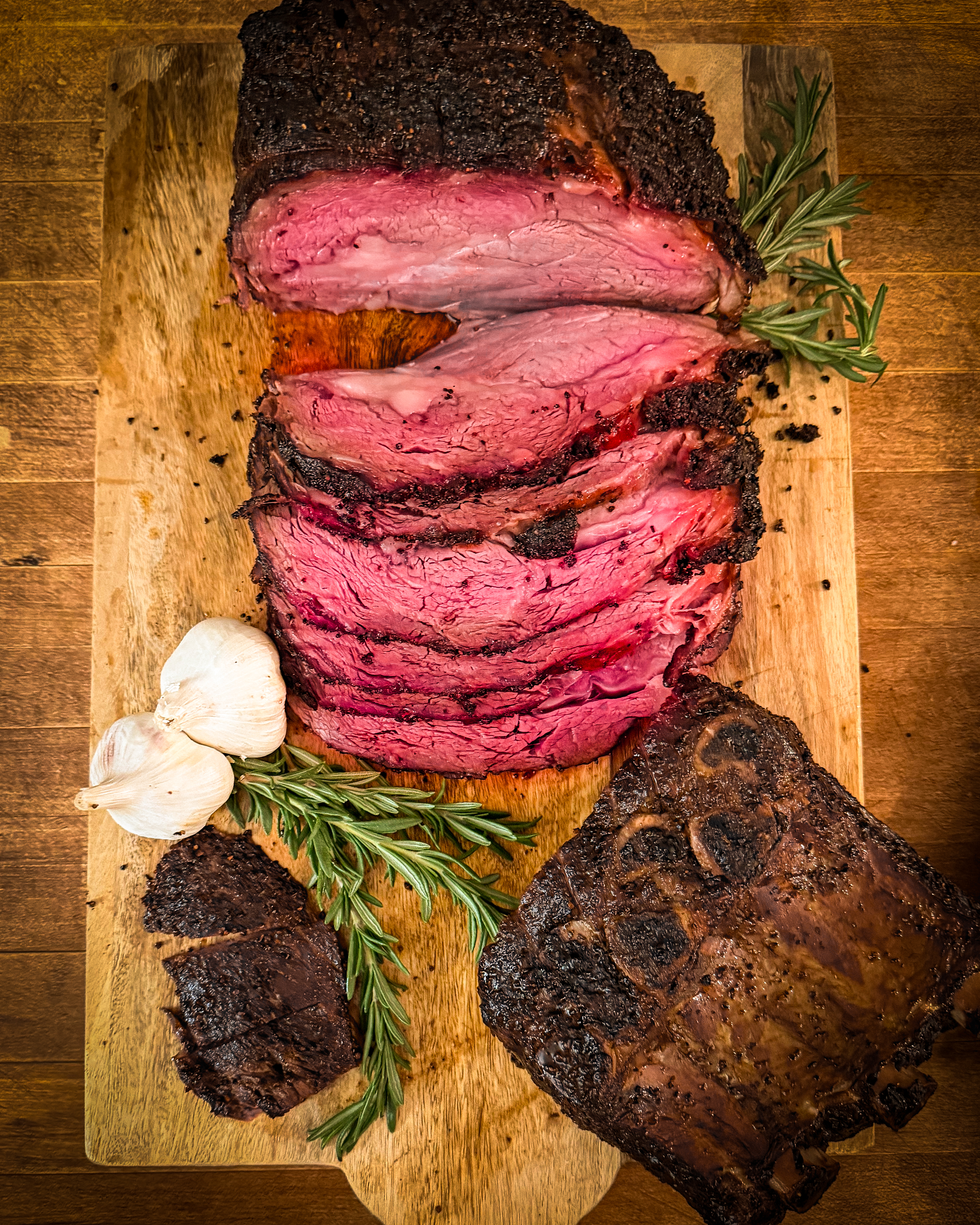 Sliced smoked prime rib roast on a cutting board with au jus